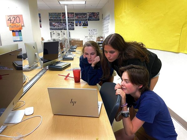 Sophomores Adelaide Middleton, Lauren Langley, and Gwyenth Ferguson (left to right) crowd around the computer to read this debate and cast their votes for which one is AI written. 