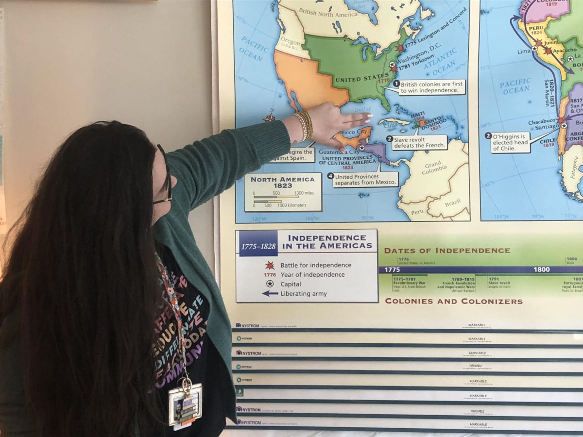 AP World History teacher Caitlin Tripp poses with one of her many maps, all of which are soon to be updated.